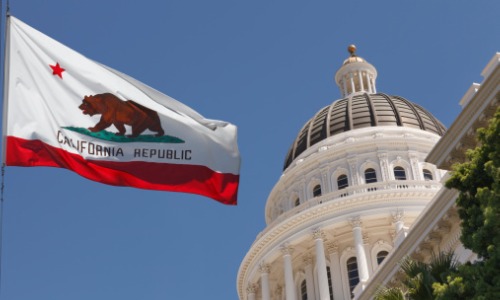 "California state capitol building with state flag flying in front"