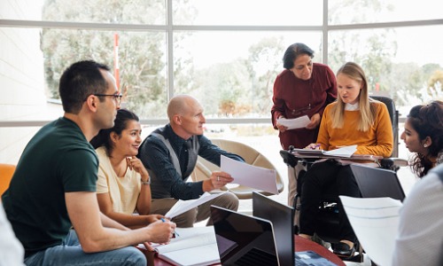 "group of six people in a sunny room, collaborating on a project"