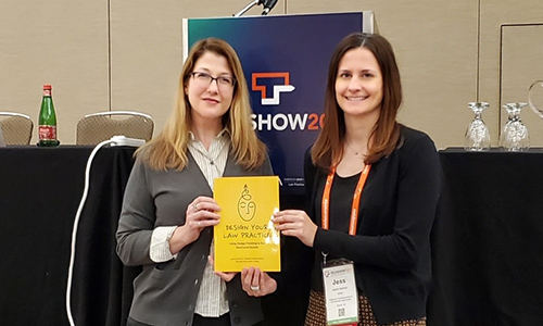 "two women standing next to each other holding yellow book"