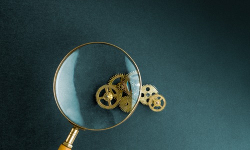 "magnifying glass looking at small cogs"
