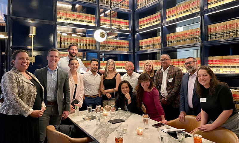 "group of smiling people around table"