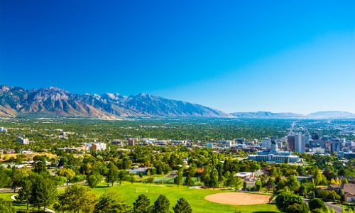 "aerial view of city on sunny day with mountains in the background"