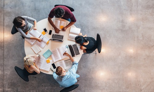 "aerial shot of five university students working at round table"