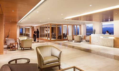 "lobby with tile floors, armchairs, end tables, reception desk, and floor-to-ceiling windows"