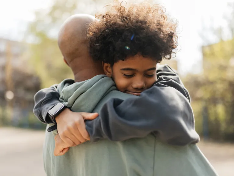 A child and an adult share a heartfelt embrace, their faces close together, conveying deep affection and emotional connection.
