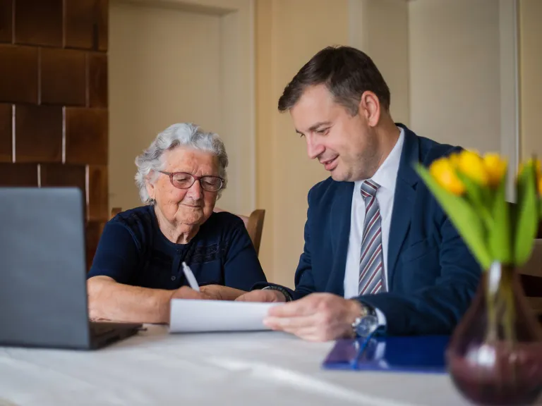 A lawyer meeting with a senior client to sign papers.