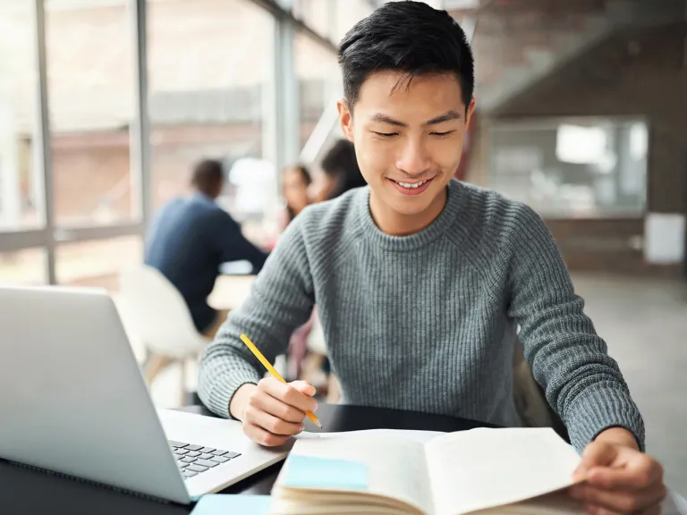 A law student studying from a book and laptop