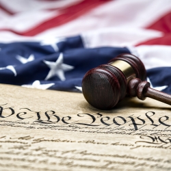 The U.S. Constitution with a gavel and flag in the background
