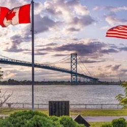 US and Canada flags by a bridge