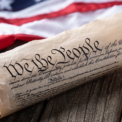 US Constitution rolled next to American flag