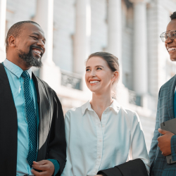 Three people smiling in front of a courthouse