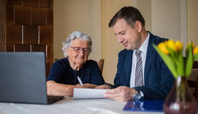 A lawyer meeting with a senior client to sign papers.
