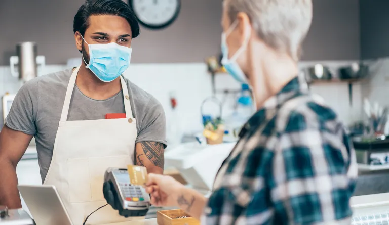 Masked merchant helping customer