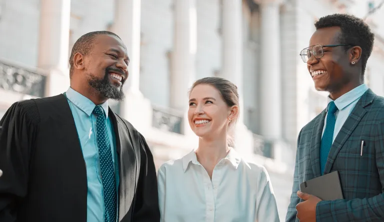 Three people smiling at a courthouse
