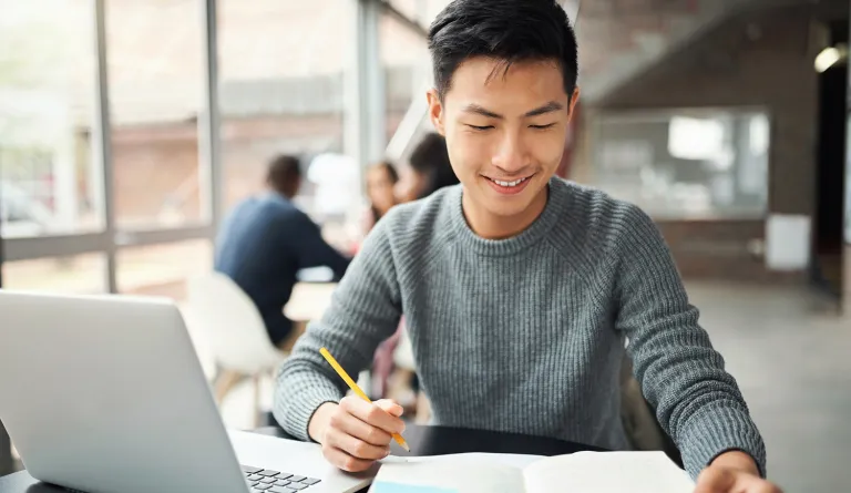 A law student studying from a book and laptop