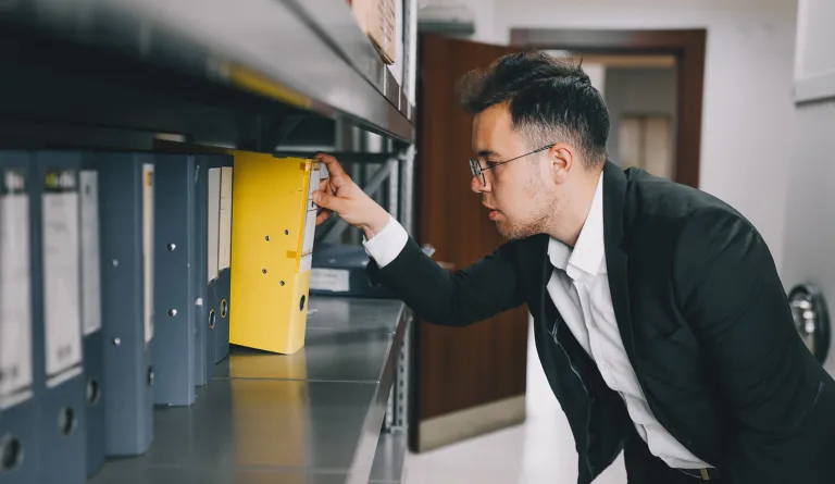 Man removing binder of files from shelf