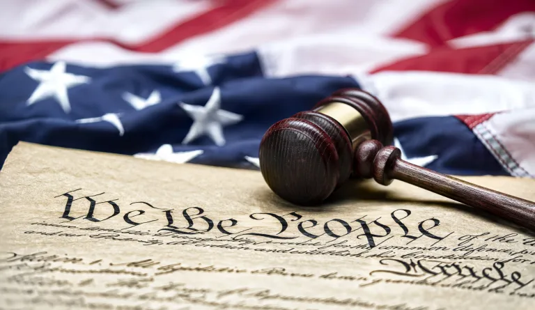 The U.S. Constitution with a gavel and flag in the background