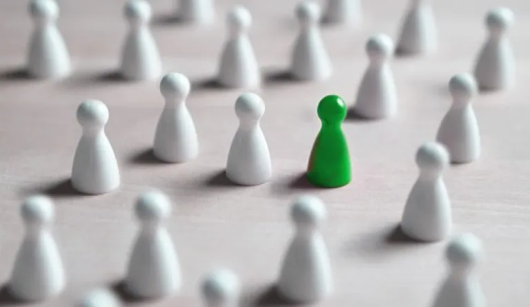 green pawn amid white pawns against white background