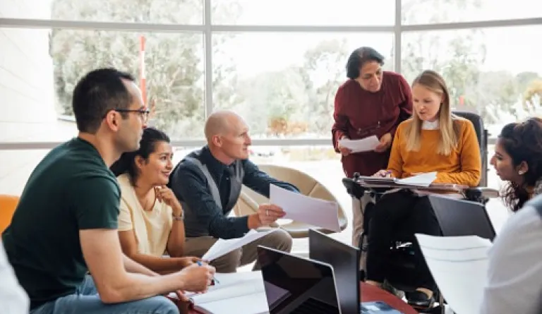 group of six people in a sunny room collaborating on a project