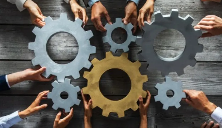 hands surrounding silver and gold clogs on tabletop