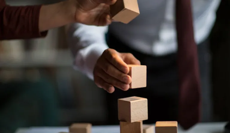 hands stacking building blocks