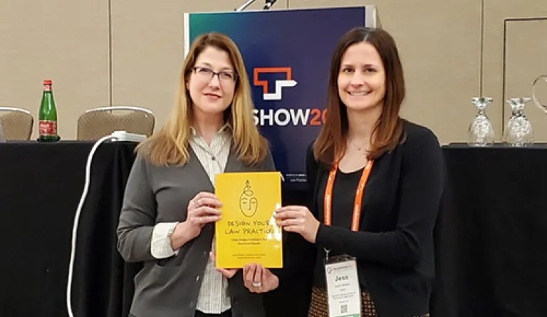 two women standing next to each other holding yellow book