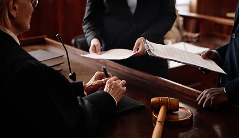 A judge conferring with two people in a courtroom