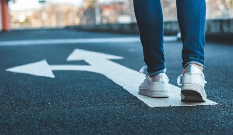 legs standing behind arrow on asphalt