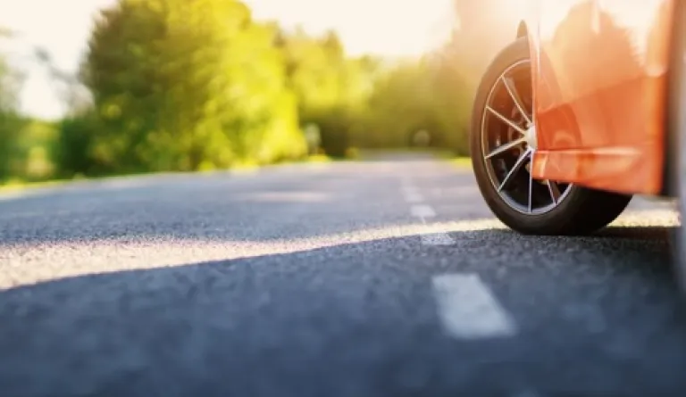 red car on asphalt road in summer