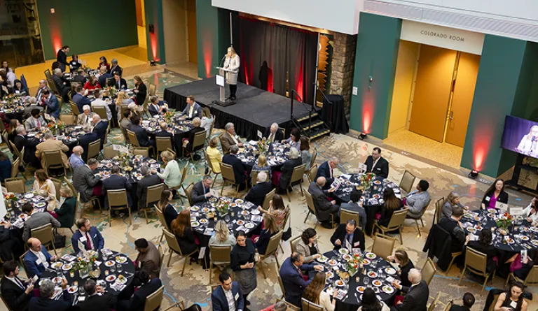 Dinner guests seated with CEO Brittany Kauffman speaks on stage