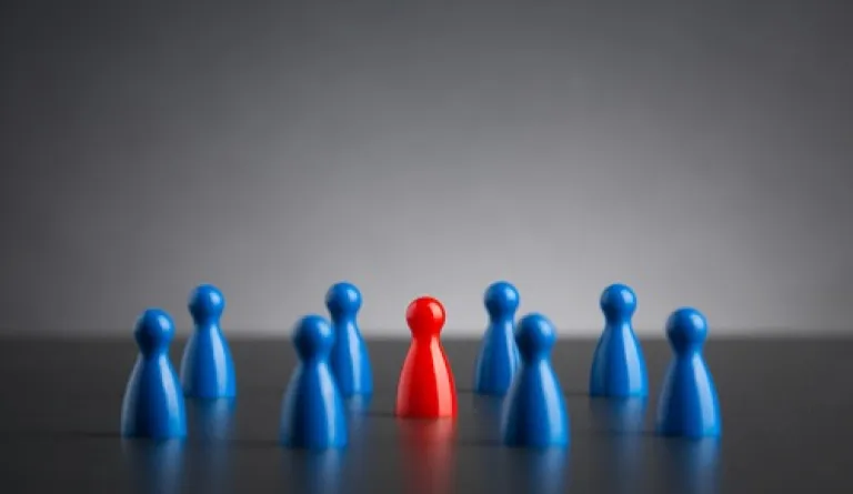 single red figure among blue group of pawns