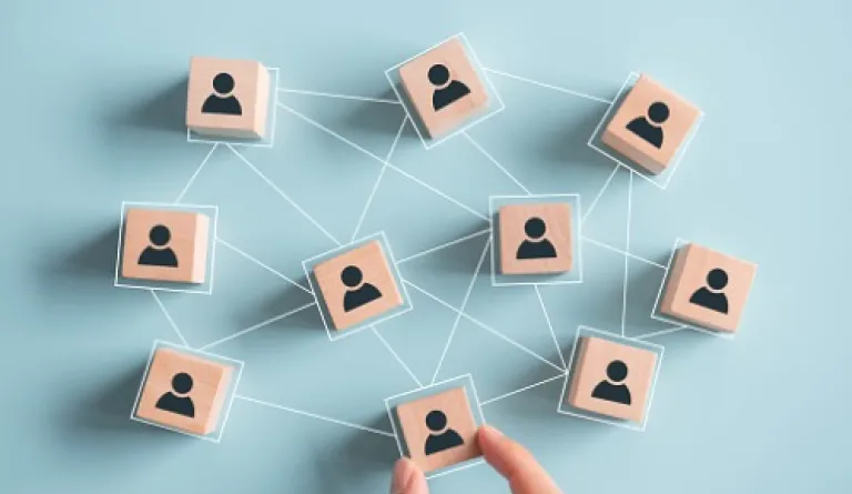 light wooden blocks with people painted on them, connected by lines, on light blue background