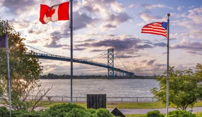 US and Canada flags by a bridge