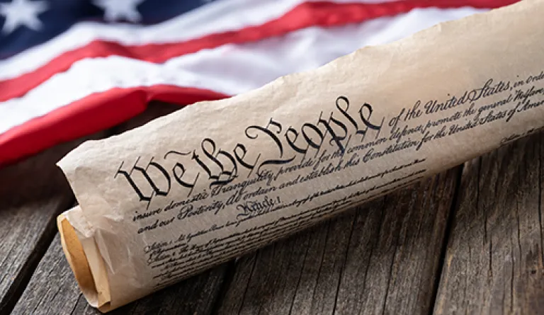 US Constitution rolled next to American flag