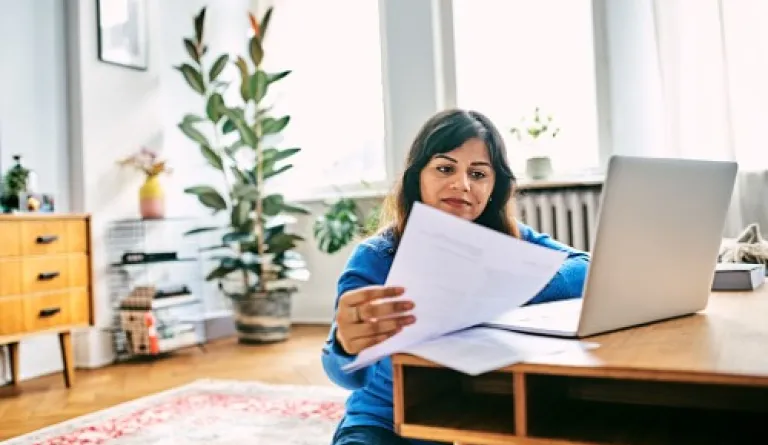 woman looking at laptop and papers