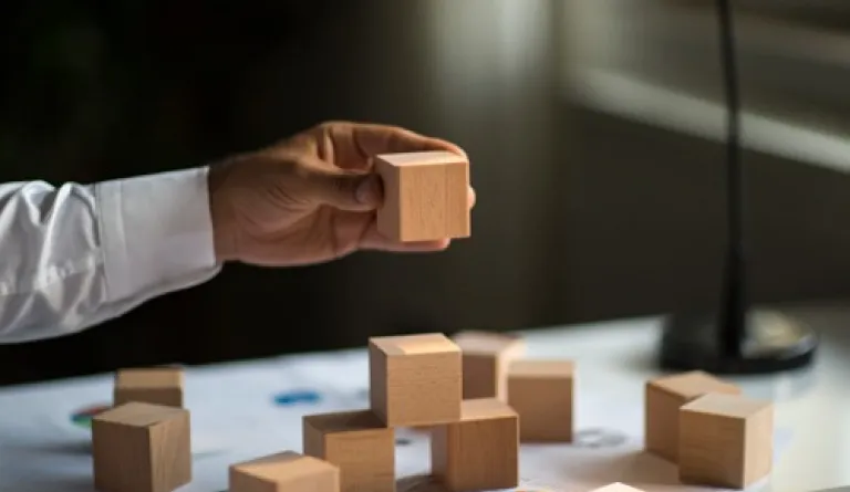 hand holding a wooden block, stacking on top of other wooden blocks
