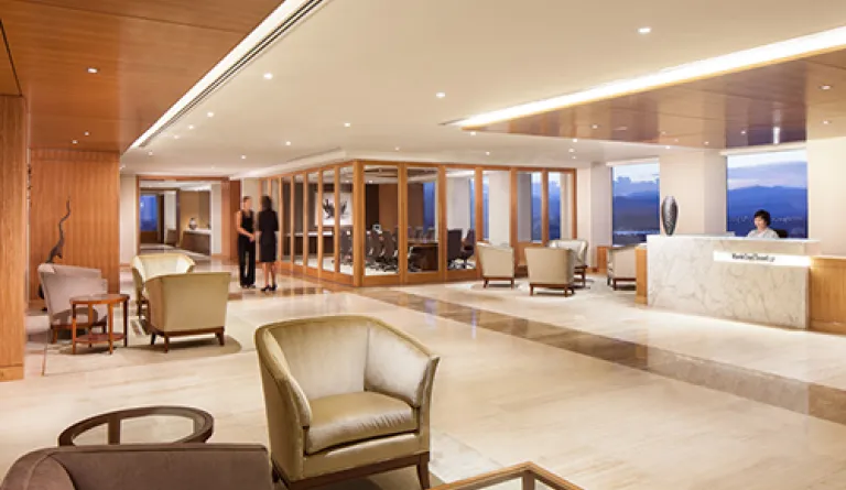 lobby with tile floors, armchairs, end tables, reception desk, and floor-to-ceiling windows