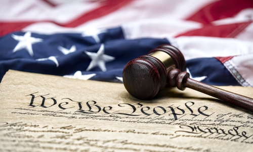 The U.S. Constitution with a gavel and flag in the background