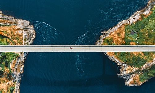 overhead view of car crossing bridge between two places