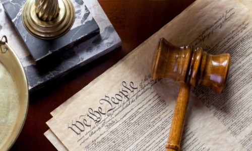 wooden gavel lying on top of U.S. Constitution