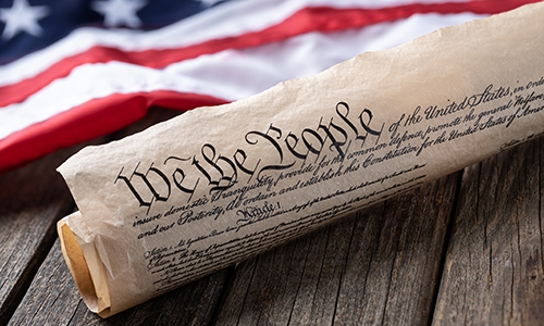 US Constitution rolled next to American flag