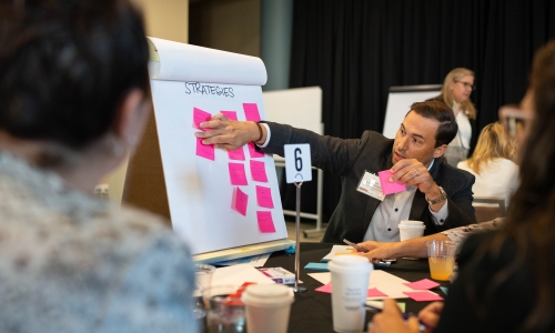 A man putting a sticky note on a display. 