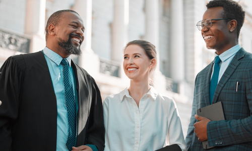 Three people smiling in front of a courthouse