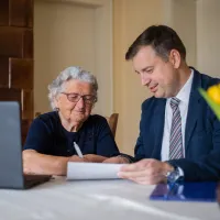 A lawyer meeting with a senior client to sign papers.