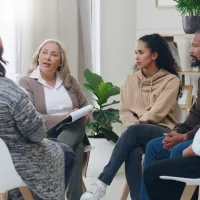 People sitting together in a group talking while one person takes notes