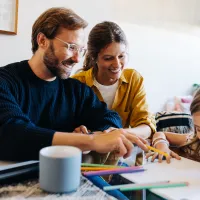 Family sitting together at a table while daughter colors