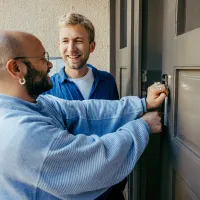 Two men unlocking a door together.