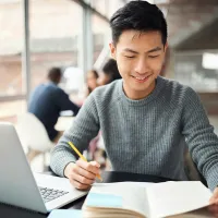 A law student studying from a book and laptop