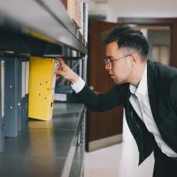 Man removing binder of files from shelf