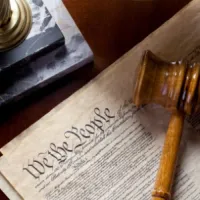 wooden gavel lying on top of U.S. Constitution